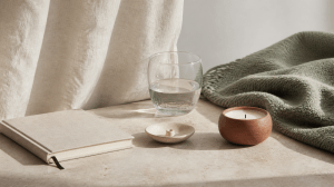 Editorial recovery still life with journal, water glass, candle and sage blanket for capacity and recovery content.