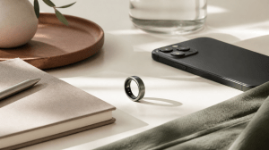 Editorial still life with a smart ring, notebook, phone and sage fabric for AbundantlyMari wearables and wellness technology content.