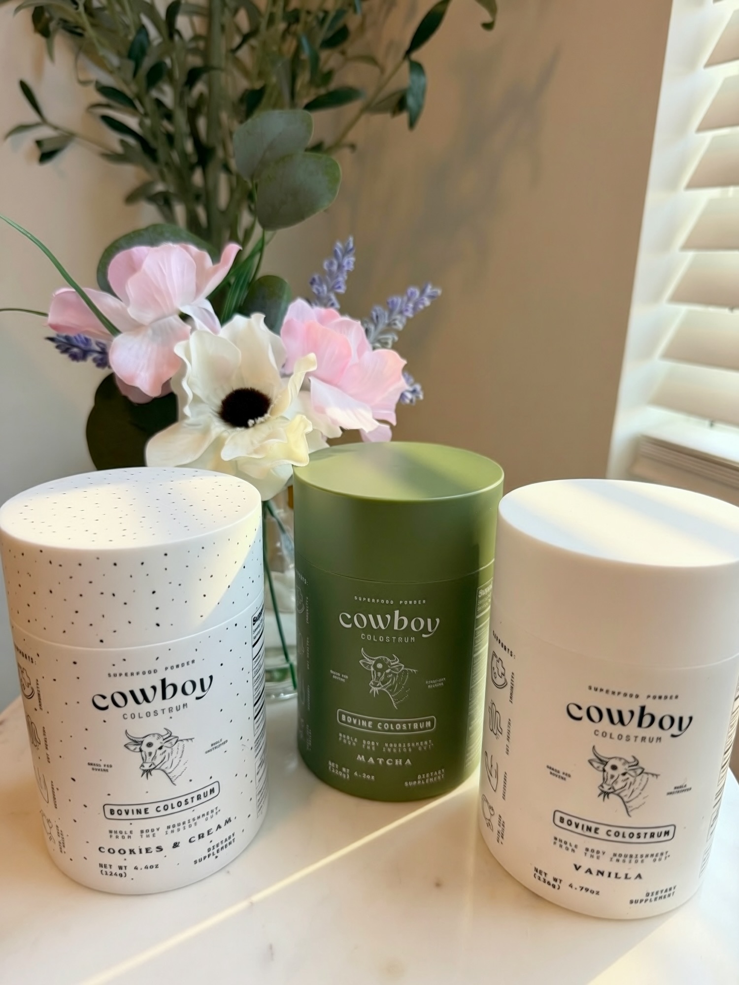 Vanilla, Matcha and Cookies & Cream Cowboy Colostrum jars photographed at home after delivery